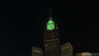 Zamzam Tower menjulang dengan cahaya berwarna hijau di atasnya.