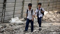 Dua orang anak sekolah nampak melintas di area revitalisasi trotoar di Jalan Salemba Raya, Jakarta.