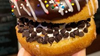 Double choco donat ini tersaji dengan isian cream dan choco chips. Toppingnya ada lelehan cokelat, whipping cream dan springkle warna-warni.  Foto: instagram @broadst_doughco