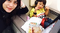 Bepergian menggunakan pesawat, Nia tampak punya camilan untuk si kecil. Sepotong roti siap untuk mengganjal perut.  Foto: instagram @niaaprilsllh