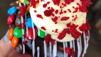 Donat red velvet ini jadi salah satu yang paling laris manis. Donat berwarna merah maroon ini diberi topping cokelat cream cheese, permen cokelat dan taburan red velvet crumble. Foto: instagram @broadst_doughco