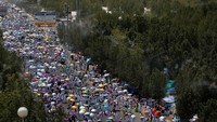 Jemaah berjalan dengan memakai payung. REUTERS/ Umit Bektas.