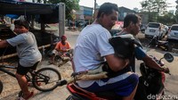 Pedagang mengirimkan kambing dengan sepeda motor.
