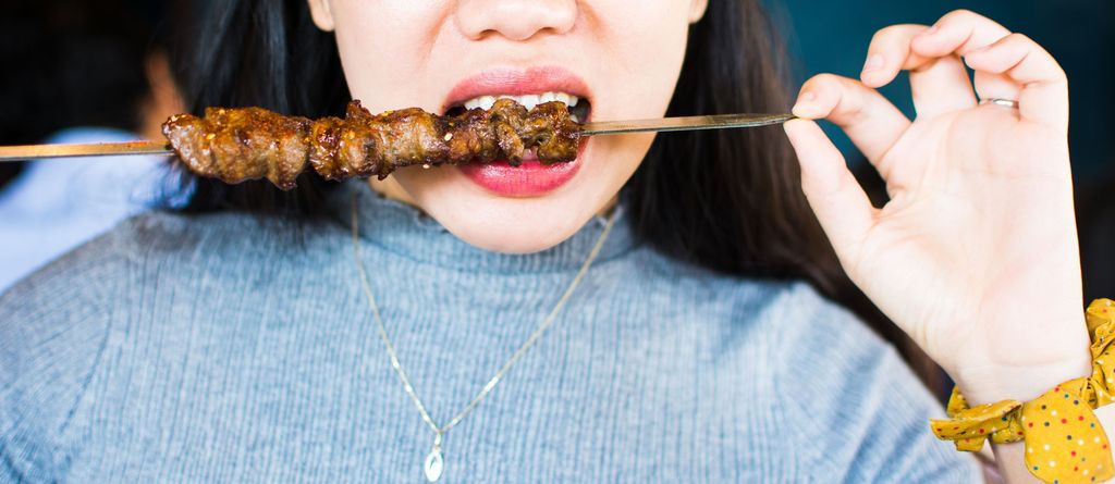 Woman eating Chinese barbeque close up