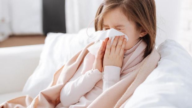 Sick little asian girl wiping or cleaning nose with tissue on her hand