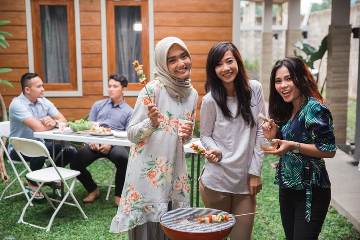 having barbecue on the grill with a group of friends in the backyarda