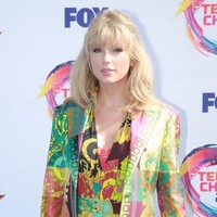 Busana tersebut terdiri dari bodysuit bermotif klasik khas Versace dalam sapuan palet pelangi. Blazer senada turut menyempurnakan gayanya. (Foto: Getty Images)