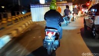 Pengendara sepeda motor yang mengenakan helm berbentuk tabung elpiji 3 kg melintas di kawasan Bekasi.