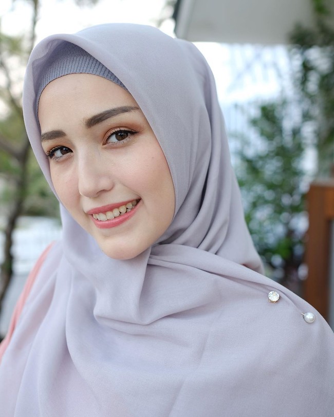 Adelia Pasha memadukan tuspin mutiara dengan hijab warna abu-abu dan inner rajut dengan tone senada. Foto: Dok. Instagram @adeliapasha