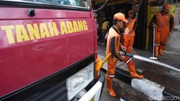 Petugas PPSU menyemprotkan air dari mobil damkar.