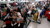 Penampakan sejumlah penumpang yang menunggu informasi terkait penerbangan mereka usai aksi unjuk rasa kembali terjadi di Bandara Internasional Hong Kong, Selasa (13/8/2019).