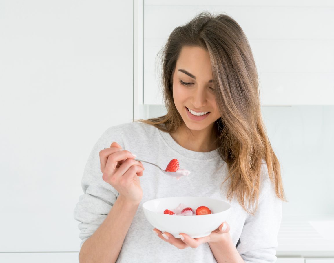 Woman  holding smoothie bawl with organic yogurt, berries and mint. Homemade yogurt in girl's hands served with raspberry, strawberry and blueberry. Breakfast. snack. Healthy eating, lifestyle concept