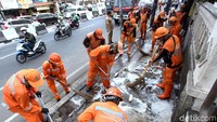 Pasukan oranye bersama petugas damkar bekerja bakti membersihkan trotoar.