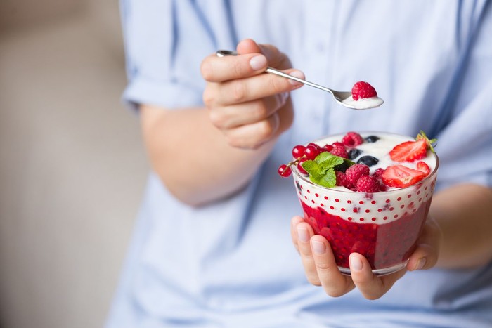 yoghurt Woman holding smoothie bawl with organic yogurt, berries and mint. Homemade yogurt in girls hands served with raspberry, strawberry and blueberry. Breakfast. snack. Healthy eating, lifestyle concept