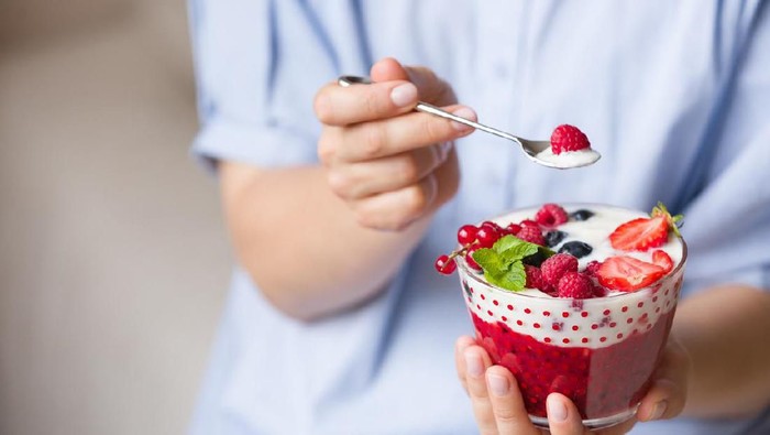 Woman  holding smoothie bawl with organic yogurt, berries and mint. Homemade yogurt in girls hands served with raspberry, strawberry and blueberry. Breakfast. snack. Healthy eating, lifestyle concept