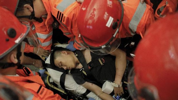 Petugas medis mengevakuasi pria yang diklaim polisi China yang menyamar oleh para demonstran Hong Kong