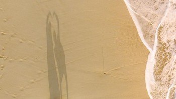 Potret sepasang wisatawan mengabadikan momen kebersamaan mereka saat bermain di pantai dengan membentuk simbol hati. Istimewa/Agora Images/@radityamaulana via Boredpanda.