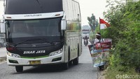 Sebuah bus melintas saat Mahmudin berjalan kaki.