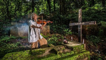 Seorang kakek memainkan alat musim di sebelah makam sang istri. Istimewa/Agora Images/@fabiansaw via Boredpanda.
