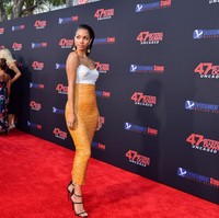 Corinne hadir dalam balutan two-tone dress rancangan Allen Schwartz yang mengekspos area bahu. Material payet yang berkilauan pada rok oranye meninggalkan kesan glamor. (Foto: Getty Images)