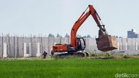 Sebuah alat berat nampak sedang beroperasi membangun area permukiman di area sawah yang berada di Kabupaten Bekasi.