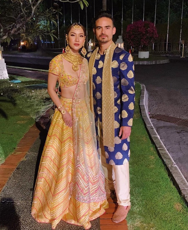 Bunga Citra Lestari (BCL) datang bersama sang suami, Ashraf Sinclair. BCL menebar pesonanya dengan gaun two-piece oranye keemasan yang mengekspos perut ratanya. Tidak ketinggalan kain sari yang tersampir di bahunya. (Foto: Instagram) 