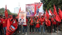 Massa buruh tersebut nampak mengenakan pakaian berwarna merah dan membawa beragam poster dan spanduk.