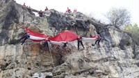 Lima pemanjat menurunkan bendera raksasa berukuran 12 meter x 8 meter itu dengan teknik rappelling saat menuruni tebing setinggi 48 meter dengan kemiringan 90 derajat.