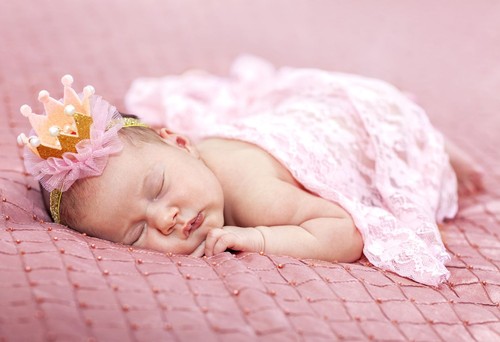 Little baby girl lies on a pink background. Photo session of a newborn baby. Professional newborn photography.