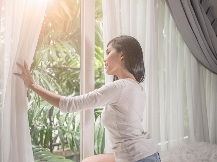 ilustrasi wanita bangun pagi hari young woman in modern apartment opening window curtains after wake up