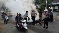 Warga bersama petugas kepolisian membersihkan sisa-sisa ban yang dibakar seusai aksi di Jalan Essau Sesa Manokwari, Papua Barat. Antara Foto/Toyiban.