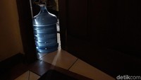 Galon air mineral digunakan untuk mengganjal pintu agar cahaya masuk menerangi ruangan.
