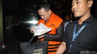 Dia terus menunduk menuju mobil tahanan.