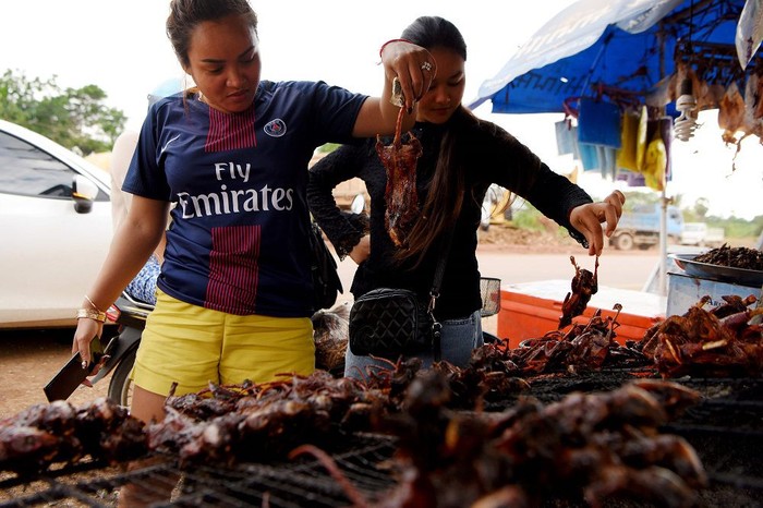 This photo taken on August 10, 2019 shows a man grilling rats at a stall in Battambang province. - Barbecued field rats are not everybodys idea of a tasty treat, but in Cambodias rural Battambang province they are popular as a cheap - and quick - snack, with small skewered ones going for 0.25USD each while larger rodents can cost 1.25USD. (Photo by TANG CHHIN Sothy / AFP)