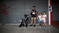 Satu keluarga tak ketinggalan dalam aksi demo. Mereka berdiri di depan sebuah toko yang tutup. REUTERS/Kim Hong-Ji.