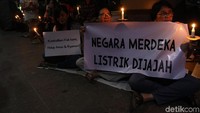 Warga duduk bersila sambil menyalakan lilin dan membentangkan poster tuntutan.