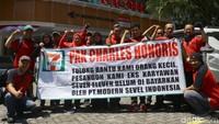 Bayar pesangon, bayar pesangon, bayar pesangon, bayar pesangon! teriak demonstran kompak menyanyikan yel-yel. Mereka kompak memakai pakaian berwarna merah.