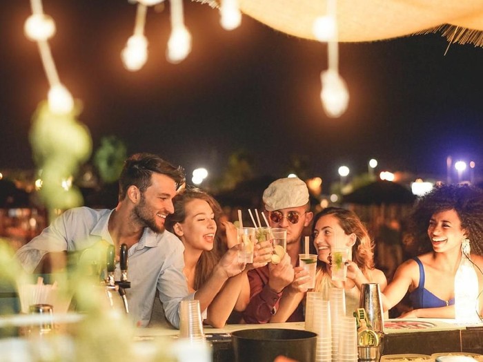 Ilustrasi Pesta Happy friends cheering and drinking cocktails at beach party outdoor - Young millennials people having fun at weekend summer night - Youth lifestyle and nightlife concept - Main focus on left guys