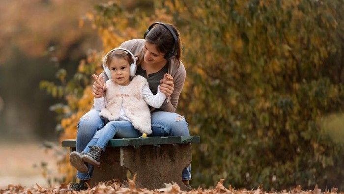 Single mother and happy cute baby girl having fun in the autumn park