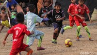 Seorang anak tengah menggiring bola melewati seumlah pemain lawan.