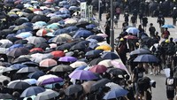 Ribuan demonstran, banyak yang memakai masker gas dan membawa payung, berjalan melintasi kawasan industri Kwun Tong. (Foto: AFP)