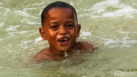 Ekspresi kebahagiaan terpancar di wajah anak-anak yang mandi di sungai tersebut.