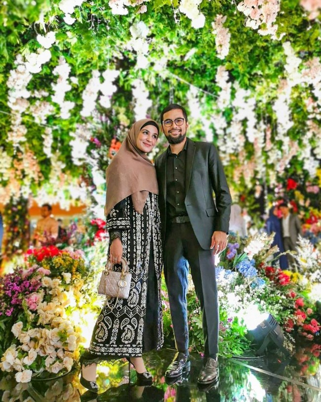 Gaun cantik rancangan Lace by Artkea membuat penampilan Shireen Sungkar tampak begitu mewah di pesta pernikahan Cut Meyriska. Shireen memadukan gaun yang kaya detail itu dengan jilbab polos yang dipakainya hingga menutup dada. Penampilannya dipermanis dengan aksesori tas Dior. Foto: Instagram