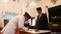 Rusli menandatangani berita acara pelantikan dengan disaksikan Jokowi.