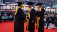 Rektor UNS Jamal Wiwoho (kiri) dan Ketua Senat UNS Adi Sulistyono (kanan) mengalungkan samir guru besar kepada Ketua Dewan Komisioner Otoritas Jasa Keuangan (OJK) Wimboh Santoso (tengah) pada acara Sidang Senat Terbuka di Auditorium UNS, Solo, Jawa Tengah, Senin (26/8/2019).