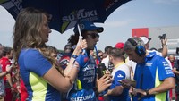 Alex Rins didampingi umbrella girl dengan seragam biru khas Suzuki. Rins menjalani balapan spesial di MotoGP Inggris setelah menjadi juara (Mirco Lazzari gp/Getty Images)