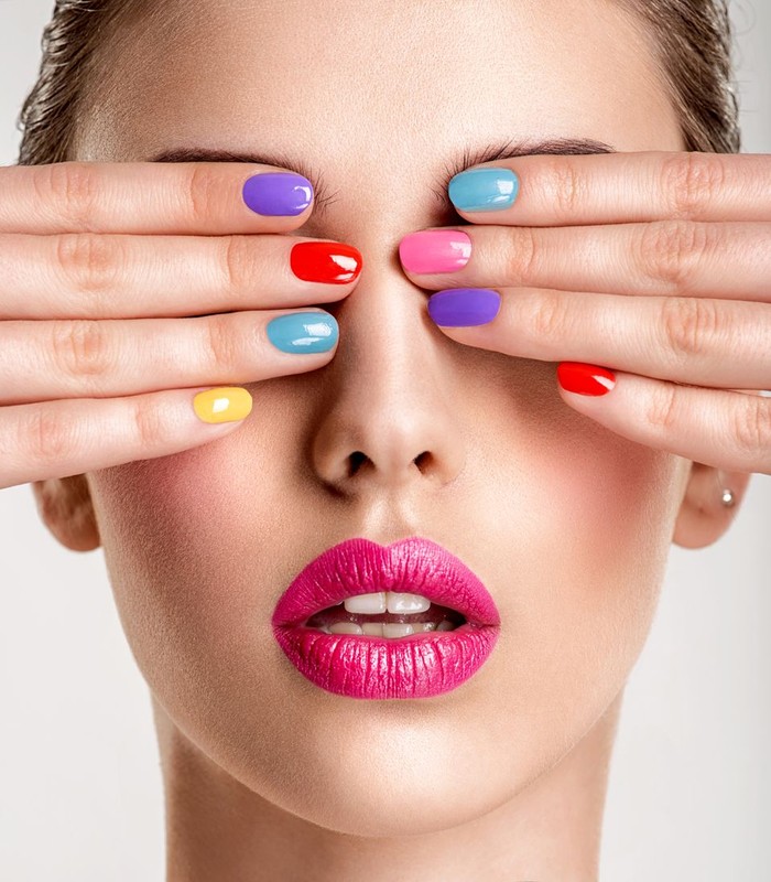 Closeup of nicely manicured female fingernails. One hand is placed on top of other, both on a white towel. Very nice french manicure with transparent nail paint. Blurry beige background. Copy space.