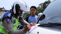 Polisi menilang pengendara yang melanggar lalu lintas.