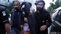 Dia terlihat mengenakan baju berwarna pink dan penutup wajah.
