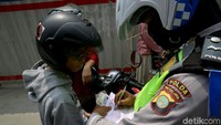 Polisi memberikan surat tilang kepada pengendara yang melanggar lalu lintas.
